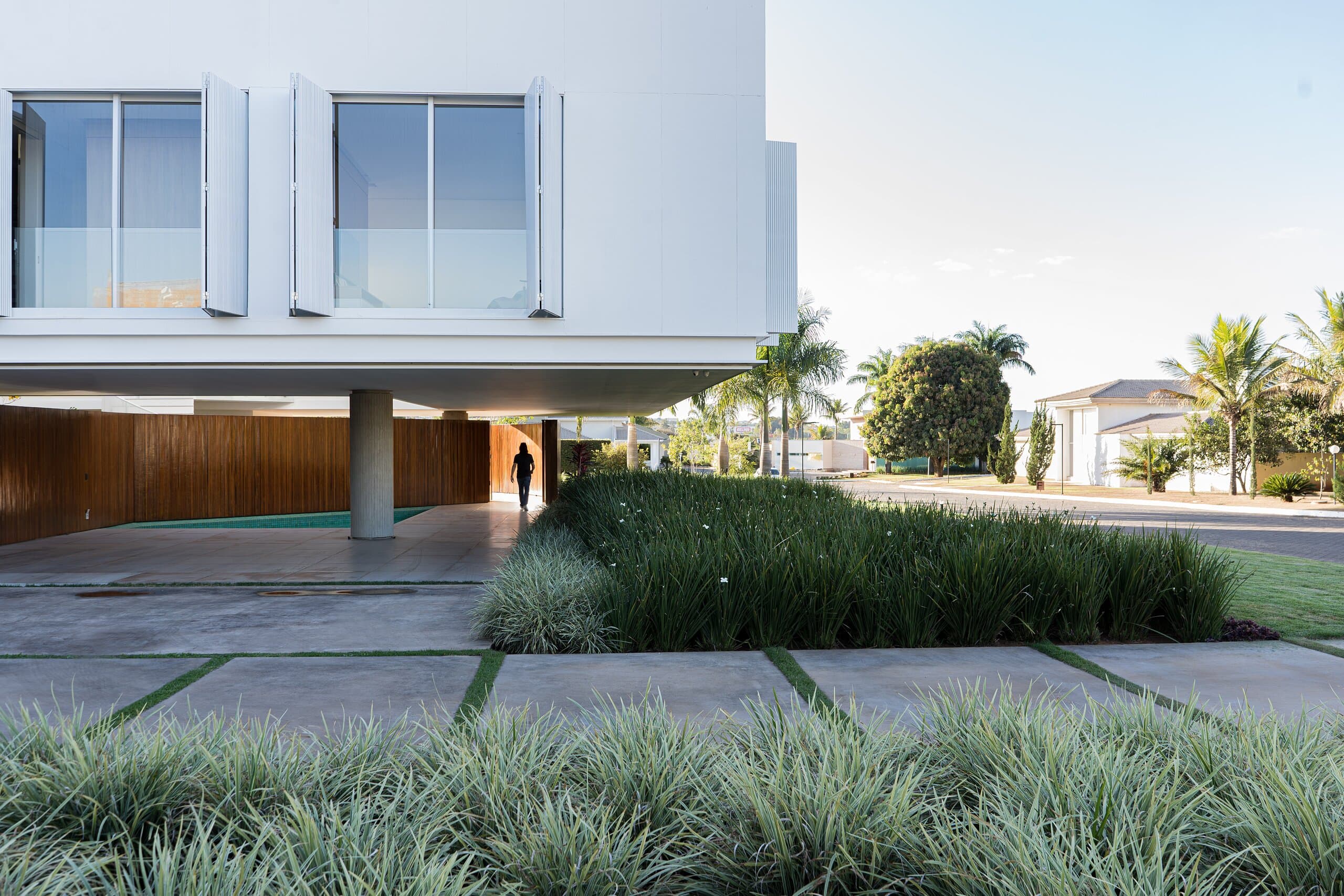 The white upper floor resting on a single column, a figure in the shade among grasses and palms.