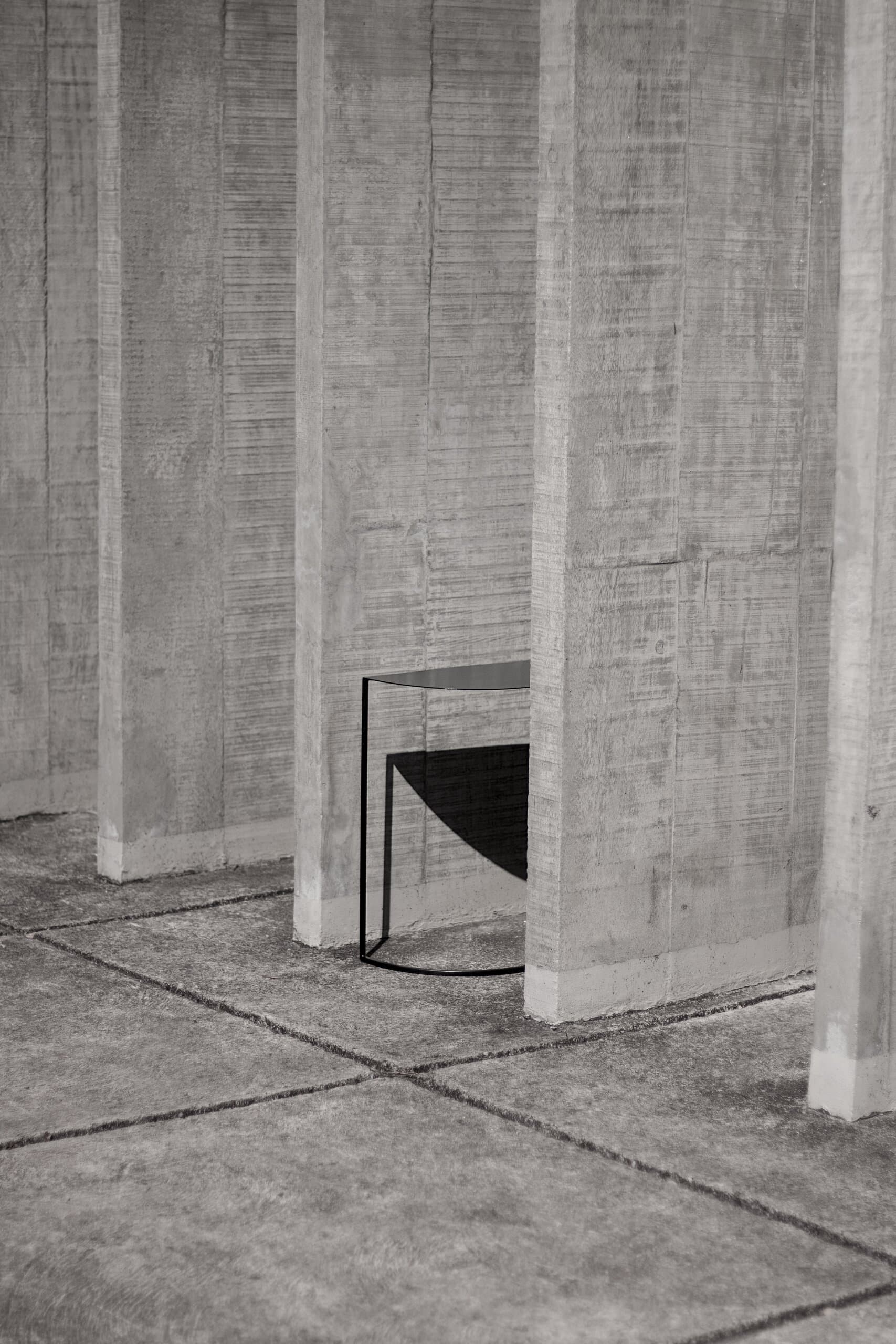 A small black table glimpsed between rows of concrete fins.