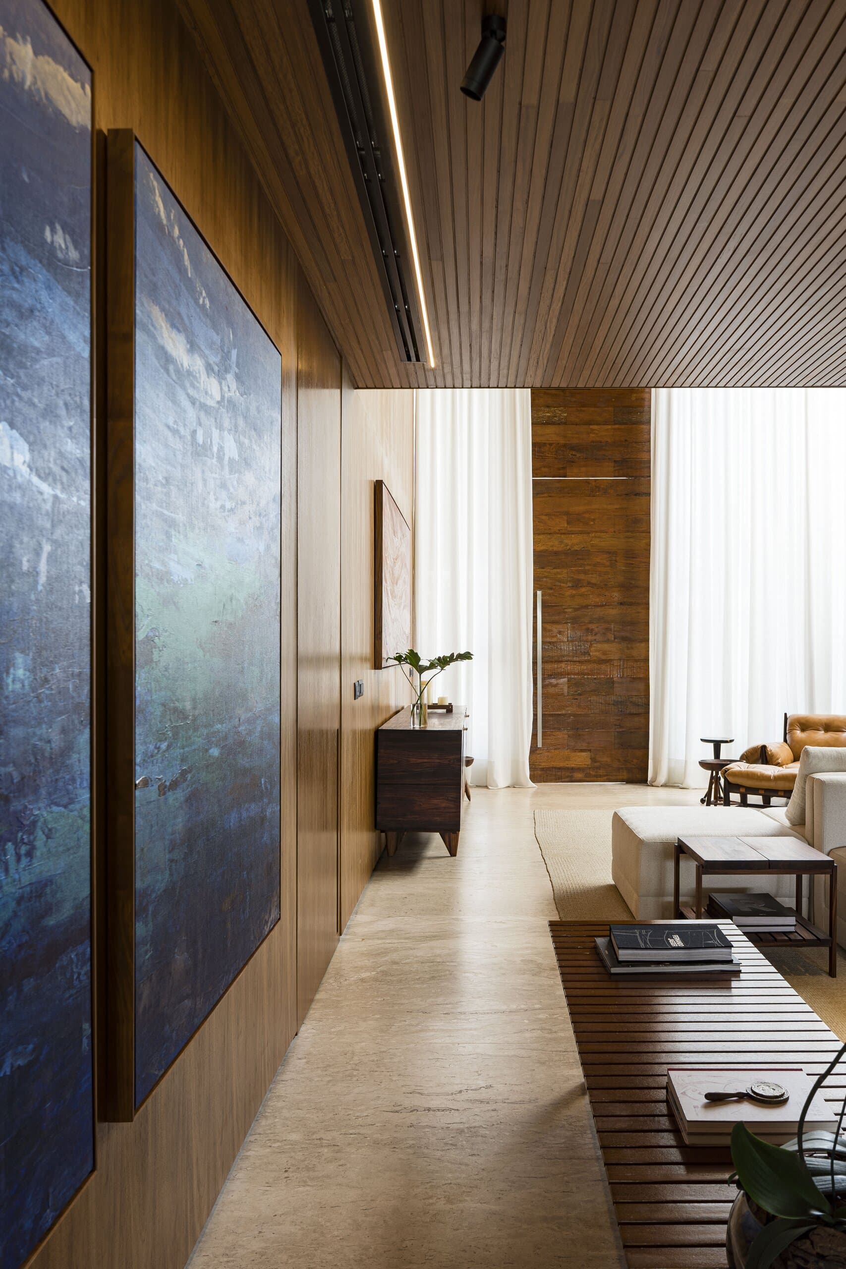 Large blue paintings along a timber wall, a slatted bench leading to the bright living room.