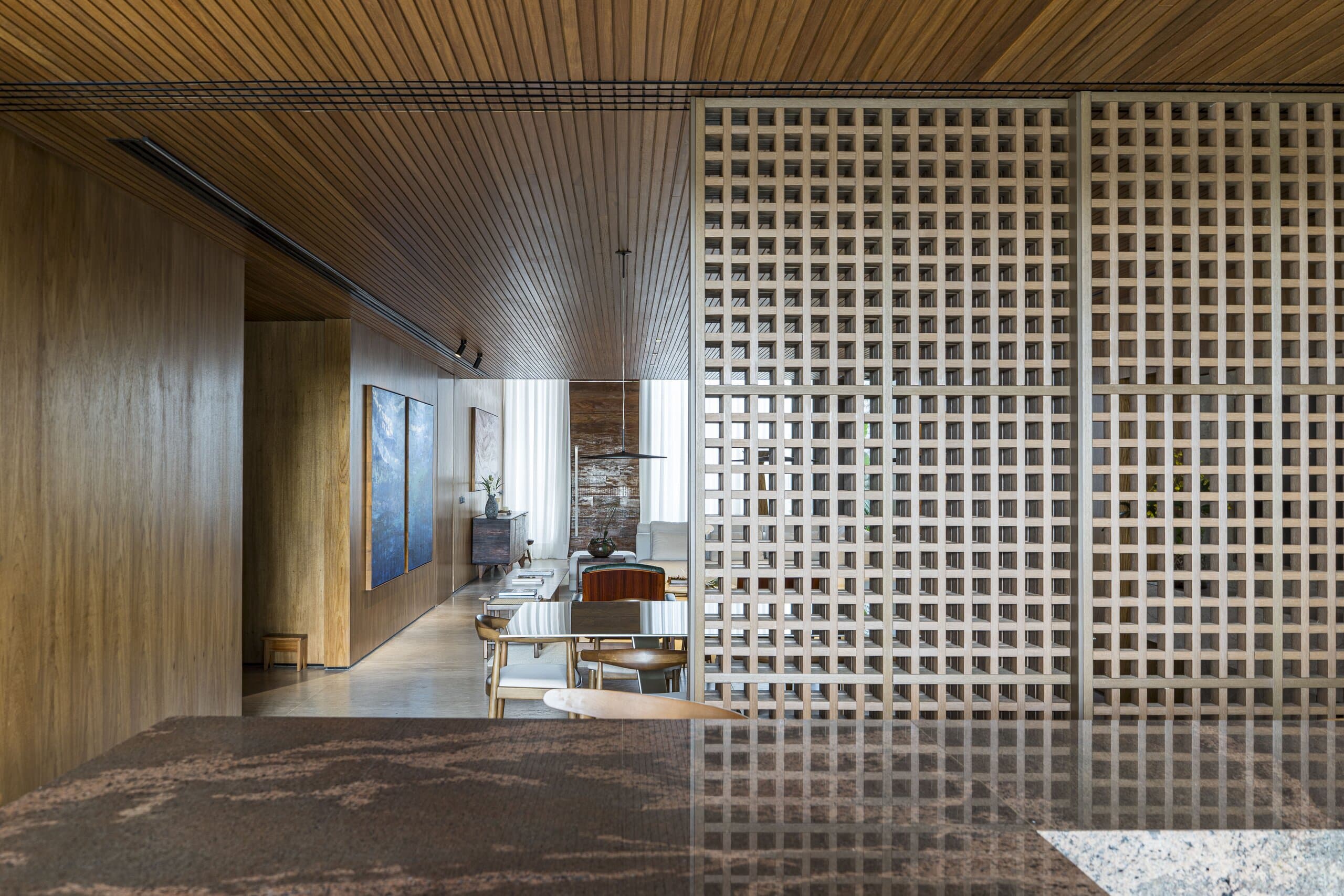 Through a white lattice screen, a timber-lined room stretches back to the blue paintings.