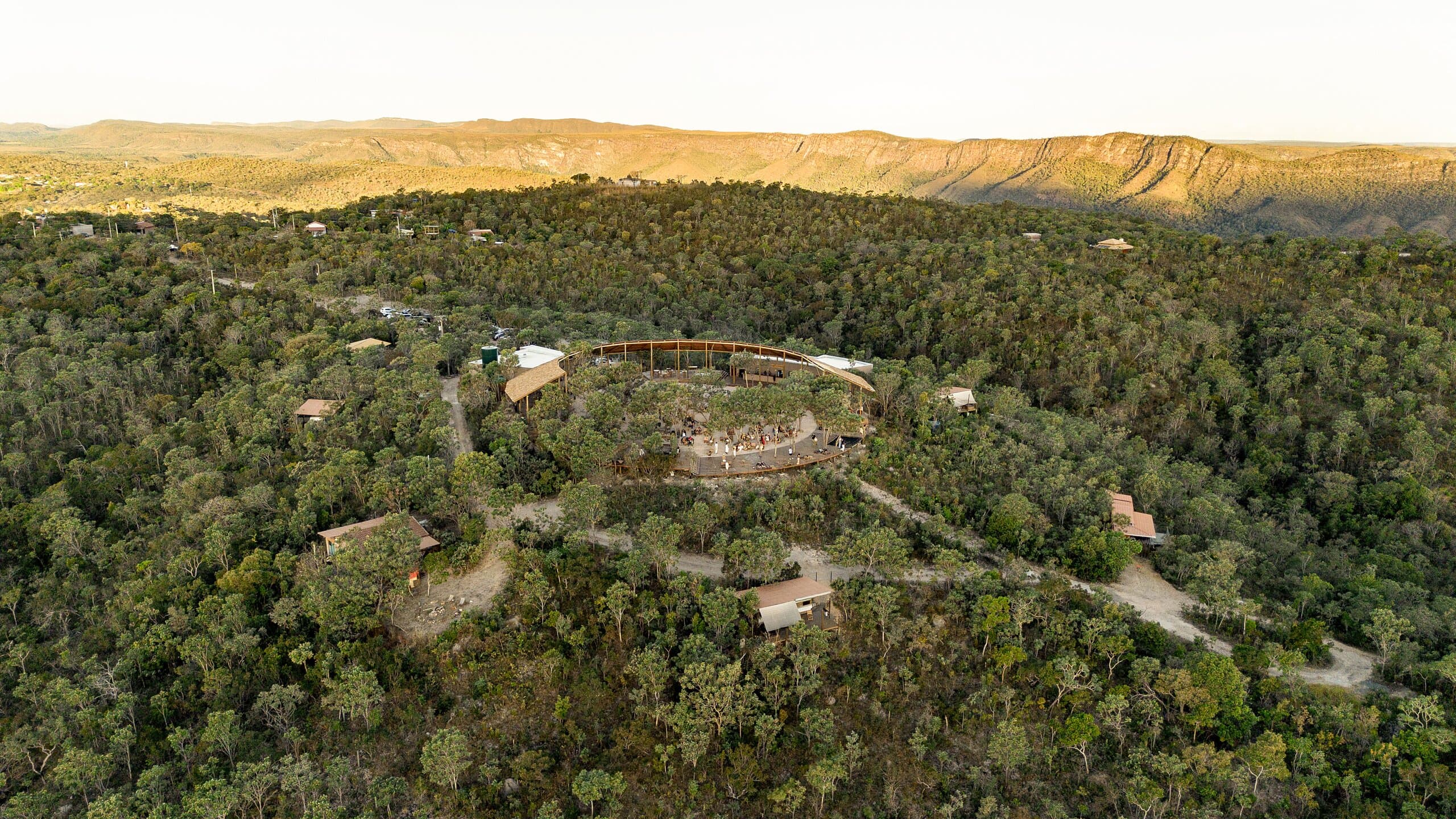 The ring of the building small within a wide wooded plateau, a golden ridge on the horizon.