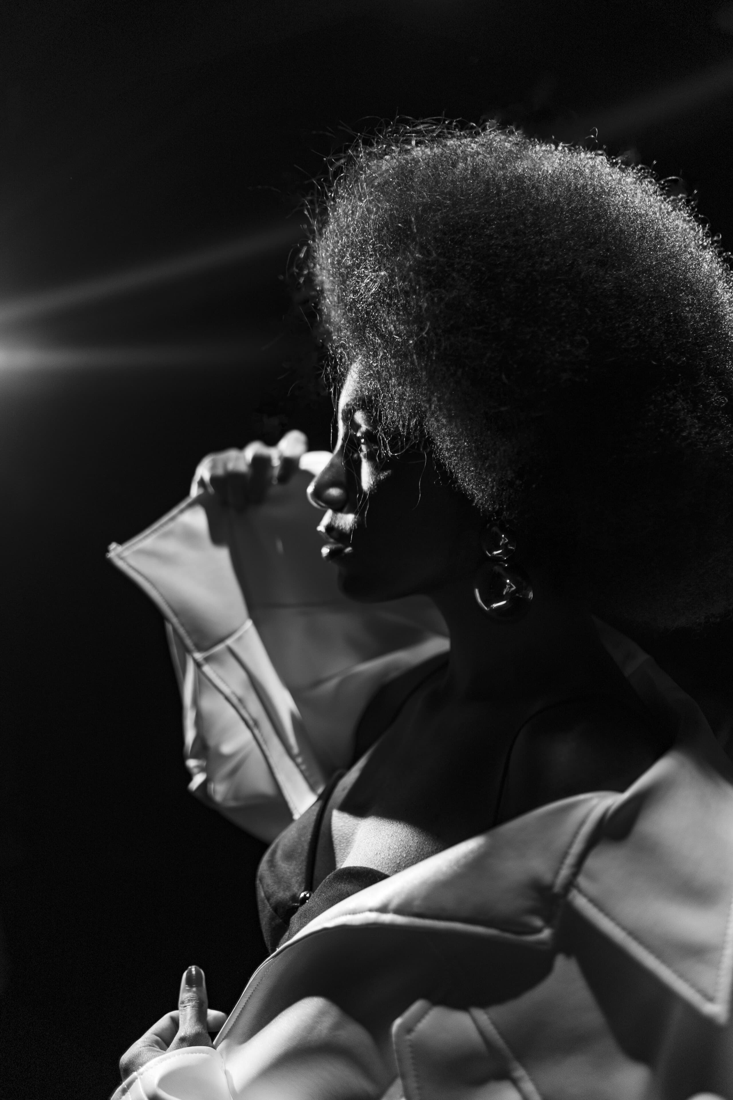 Black and white: a profile with a halo of natural hair and a sculptural white sleeve.