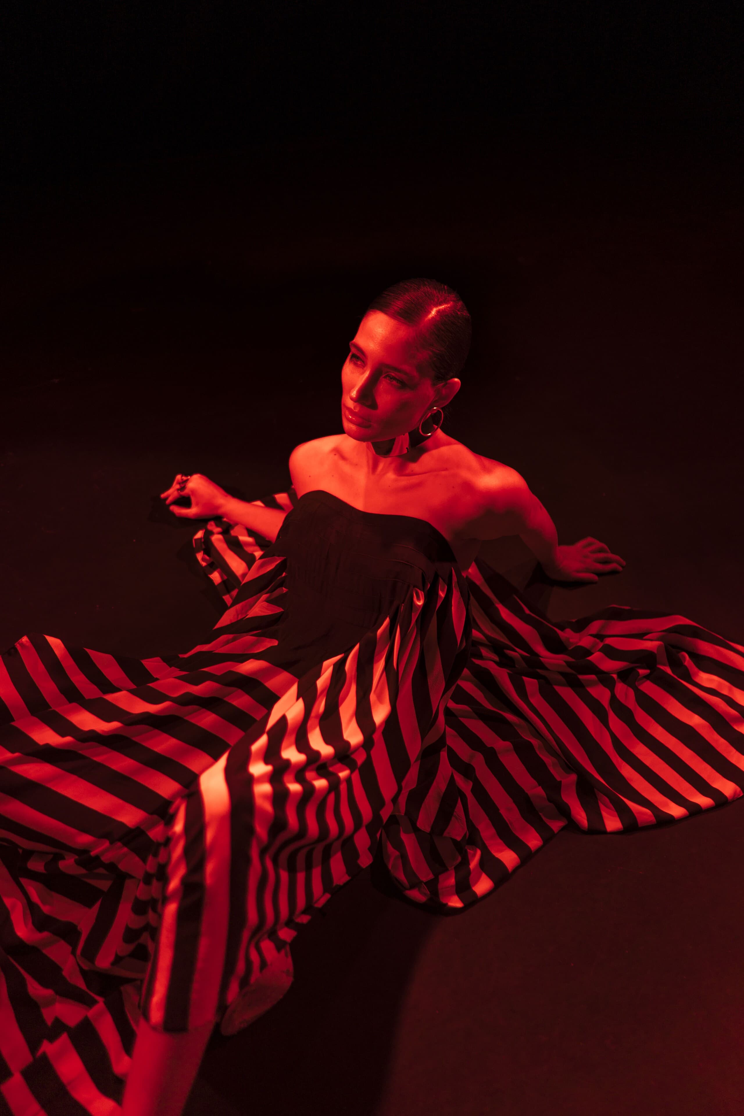 In red light, a red and black striped dress spread across the floor.